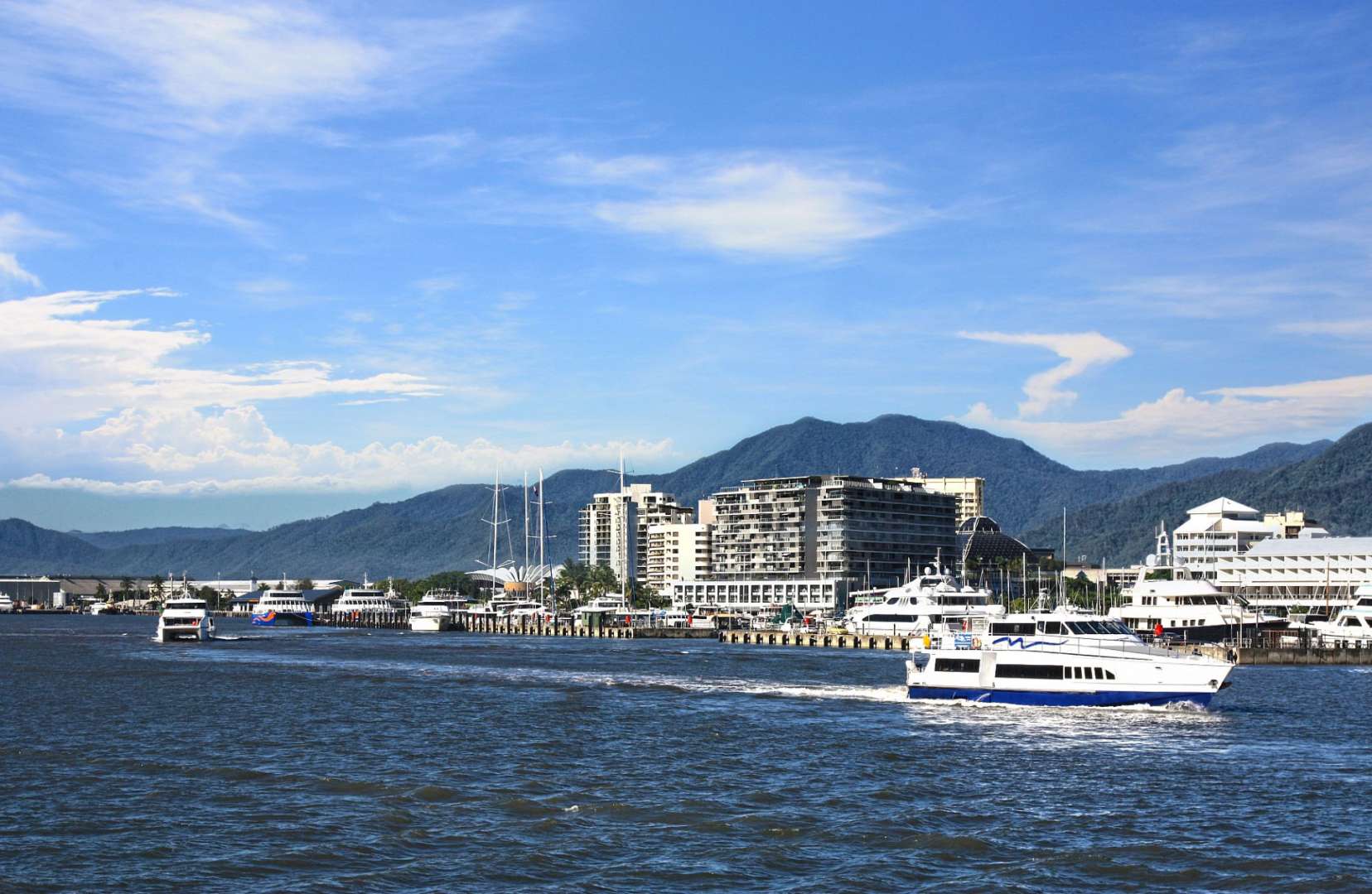 Ein Boot fährt in einem Hafen mit Bergen im Hintergrund