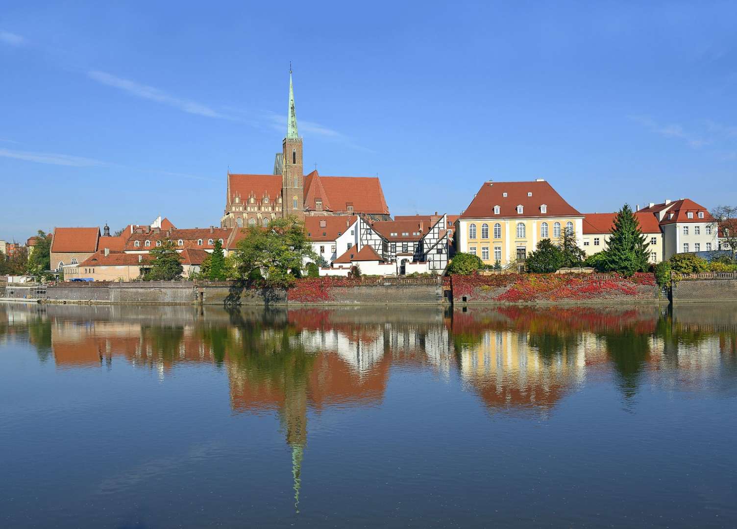 Eine Reihe von Gebäuden neben einem Fluss mit einer Kirche im Hintergrund