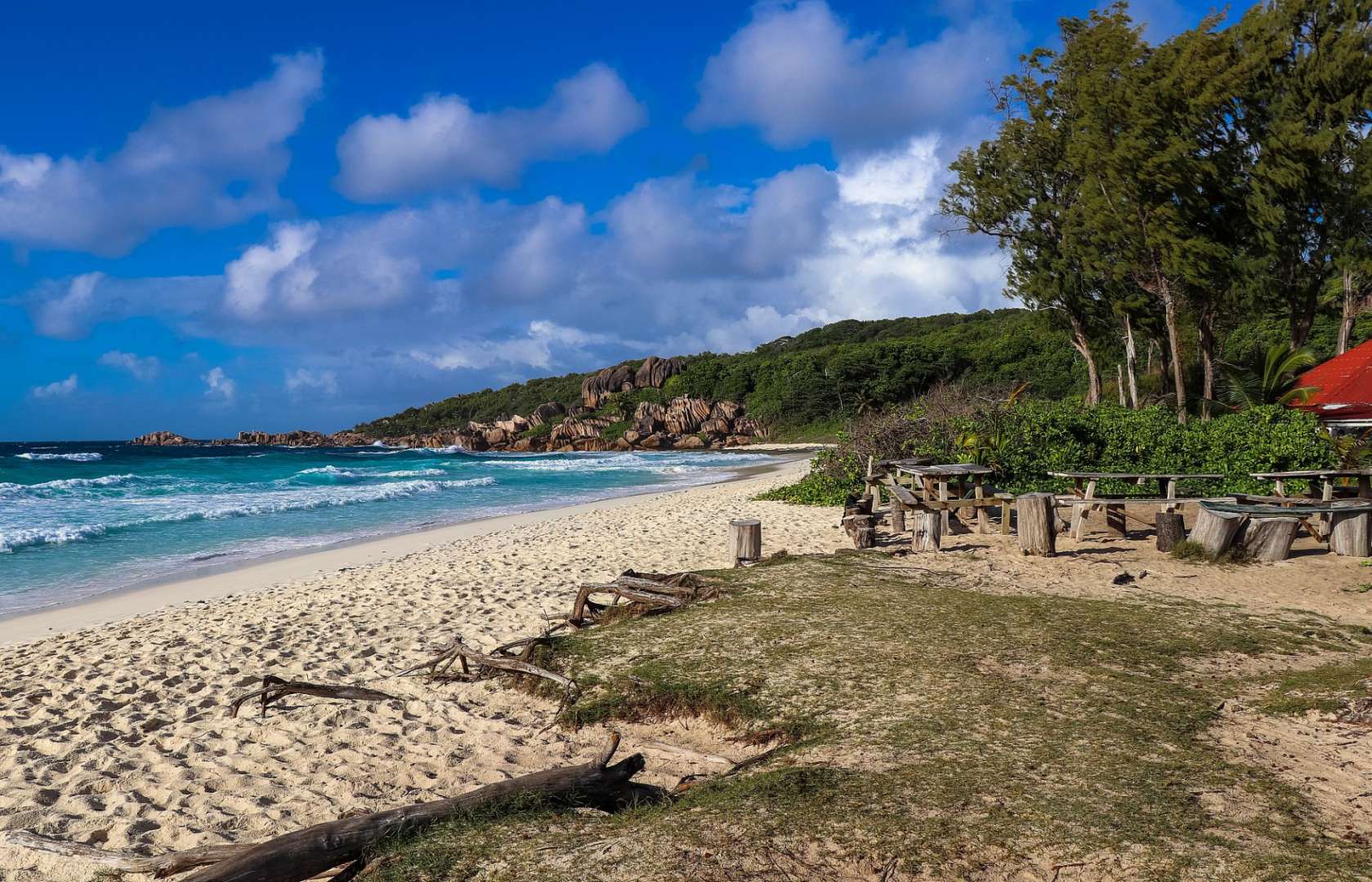 Ein weißer sandiger Strand mit einem roten Gebäude im Hintergrund