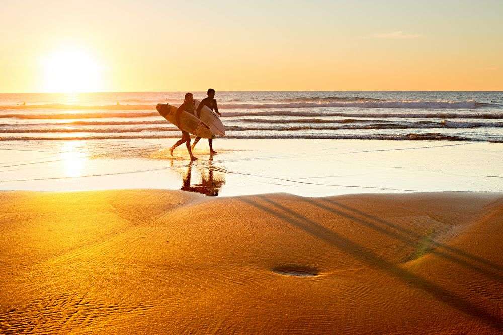Zwei Surfer gehen bei Sonnenuntergang ins Meer