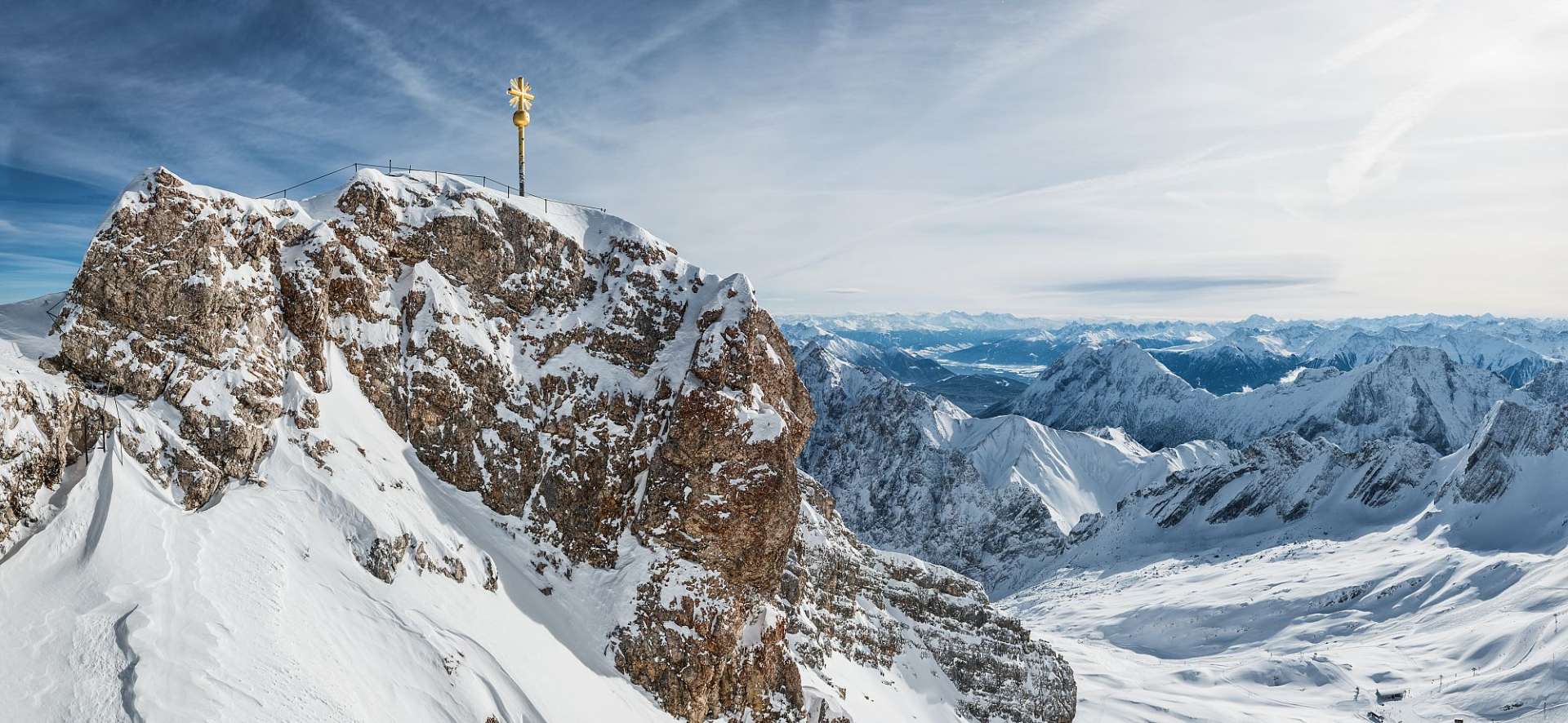 Ein goldenes Kreuz sitzt auf einem schneebedeckten Berg