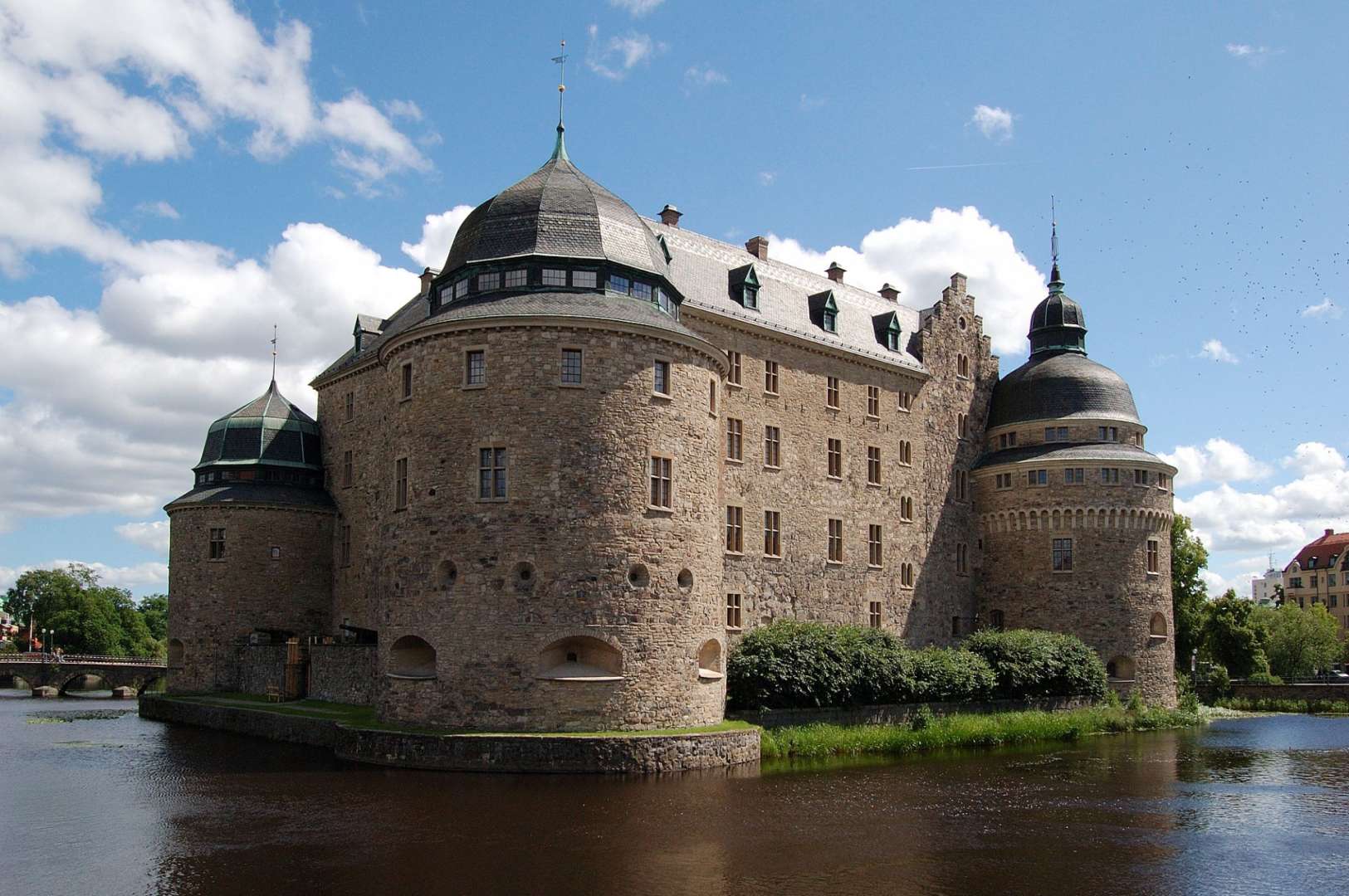 Ein großes Steingebäude mit einem Turm darauf sitzt über einem Fluss