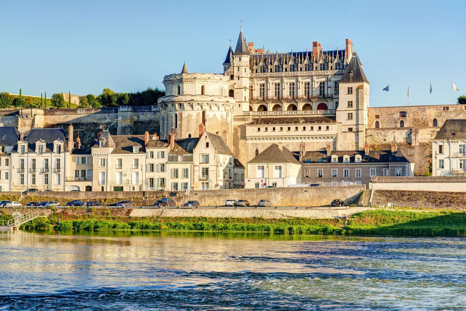 Ein großes Schloss sitzt auf einem Hügel über einem Fluss