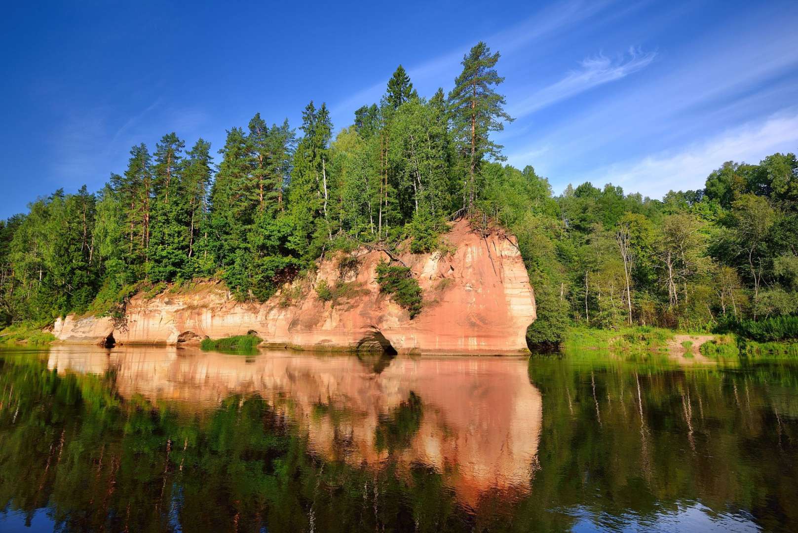 Ein Fluss mit einem roten Felsen im Vordergrund