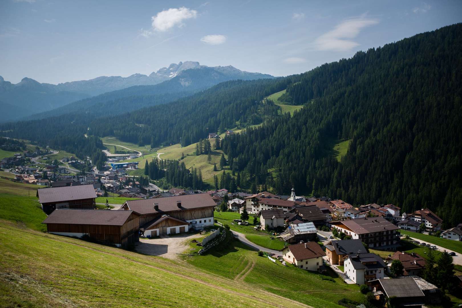 Ein kleines Dorf liegt auf einem Hügel mit Bergen im Hintergrund