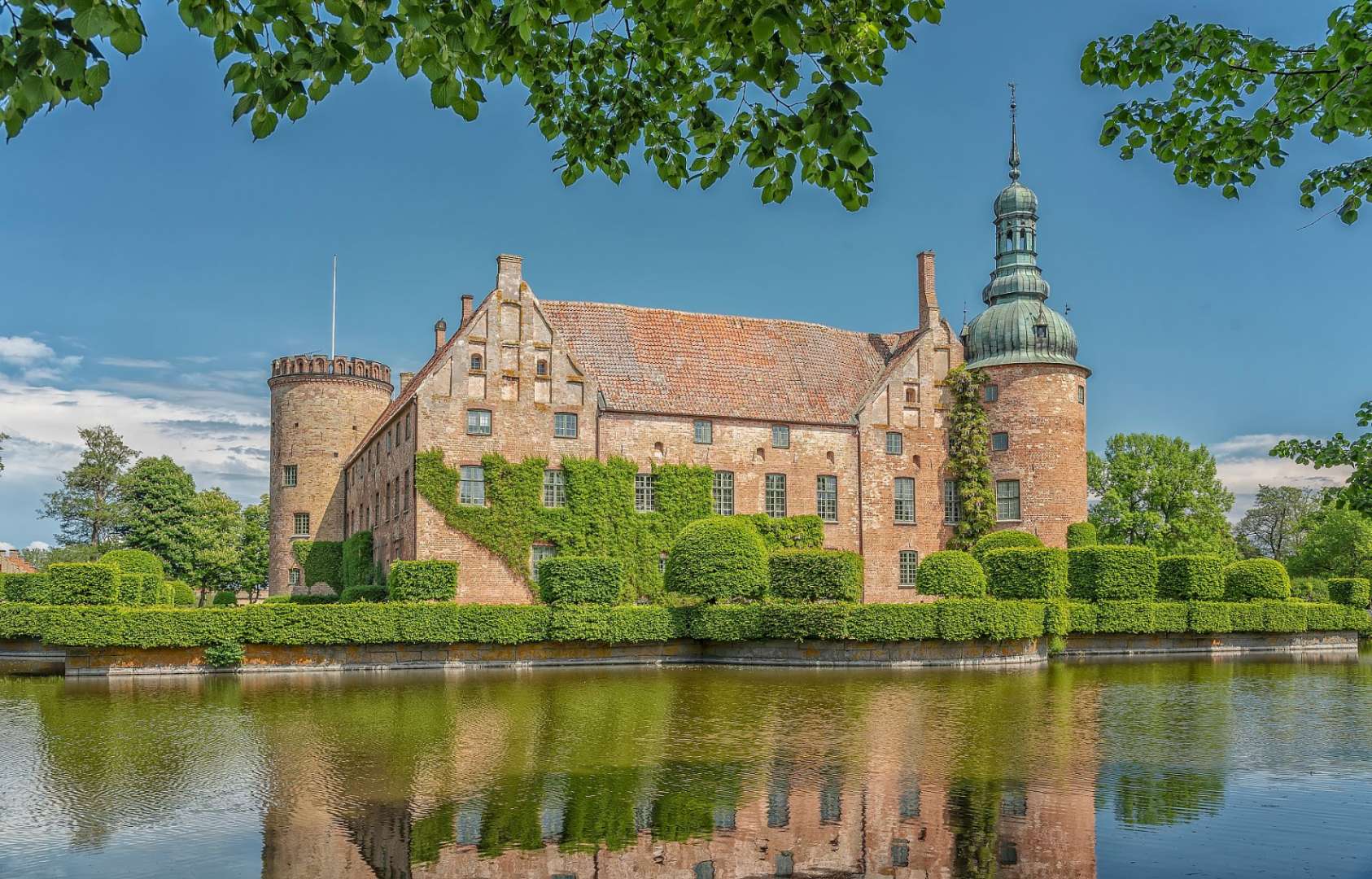 Ein großes Gebäude mit einem Turm sitzt über einem Teich