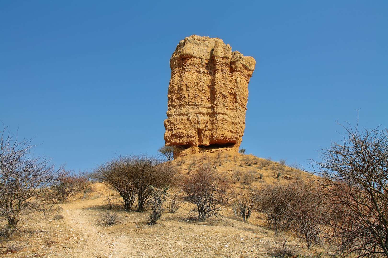 Ein großer Felsen steht auf einem Hügel in der Wüste