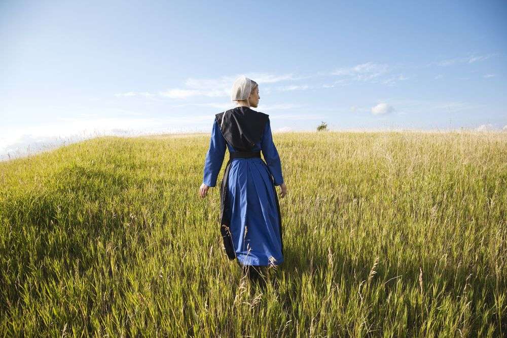 Eine Frau in einem blauen Kleid geht durch ein Feld