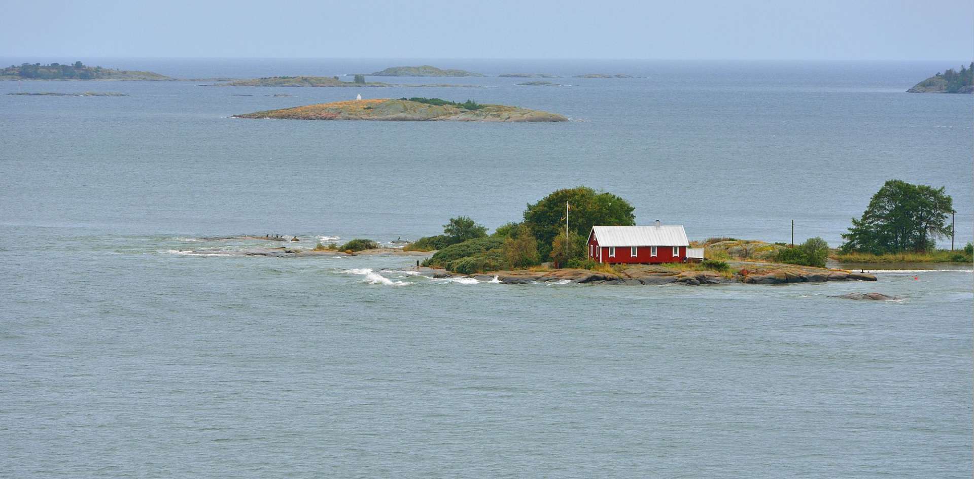 Ein kleines rotes Haus sitzt auf einer kleinen Insel im Ozean