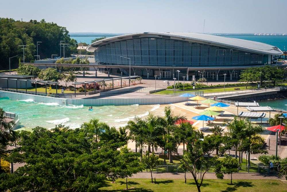 Ein großes Gebäude neben einem Strand mit bunten Sonnenschirmen