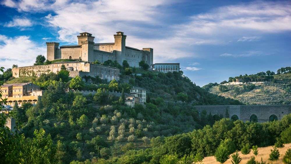 Ein großes Schloss sitzt auf einem Hügel mit Bäumen umgeben