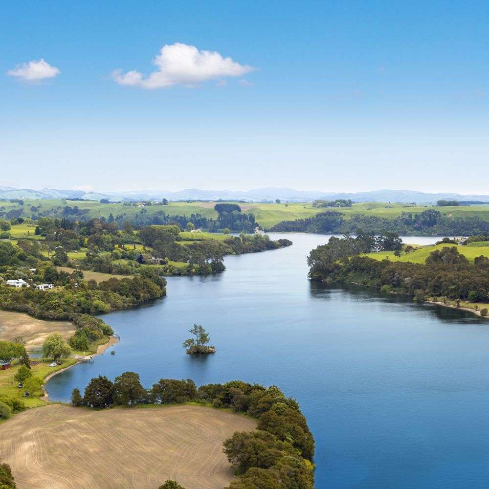 Ein großer See umgeben von Feldern und Bäumen