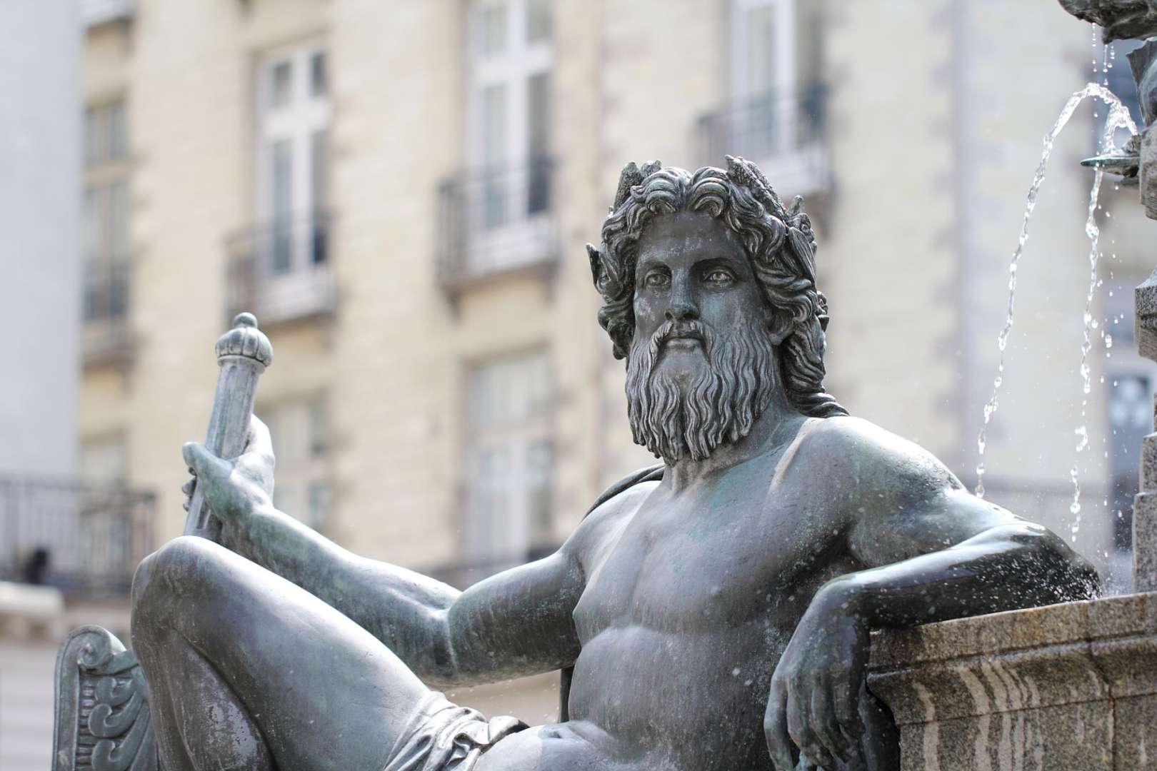 Eine Statue eines Mannes mit Bart sitzt neben einem Brunnen