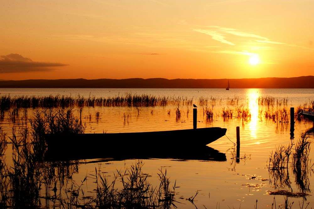 Eine Silhouette eines Bootes in einem See bei Sonnenuntergang