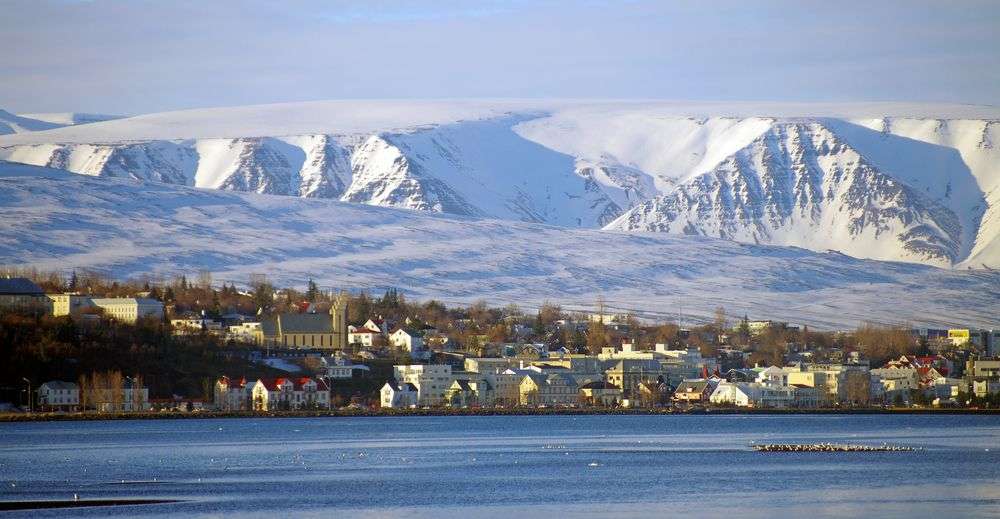 Eine Stadt an einem See mit schneebedeckten Bergen im Hintergrund