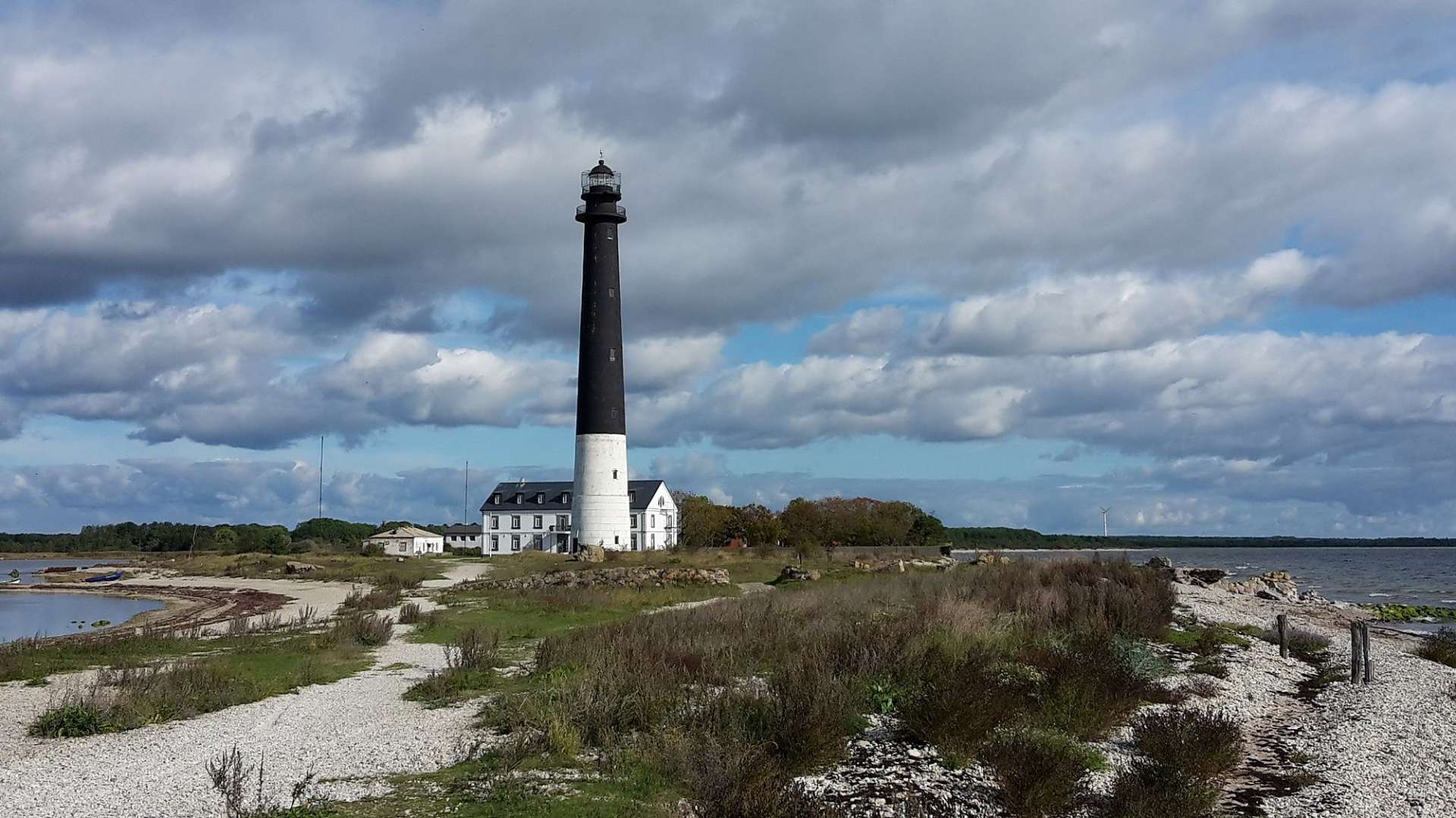 Ein schwarz-weißer Leuchtturm steht auf einer kleinen Insel