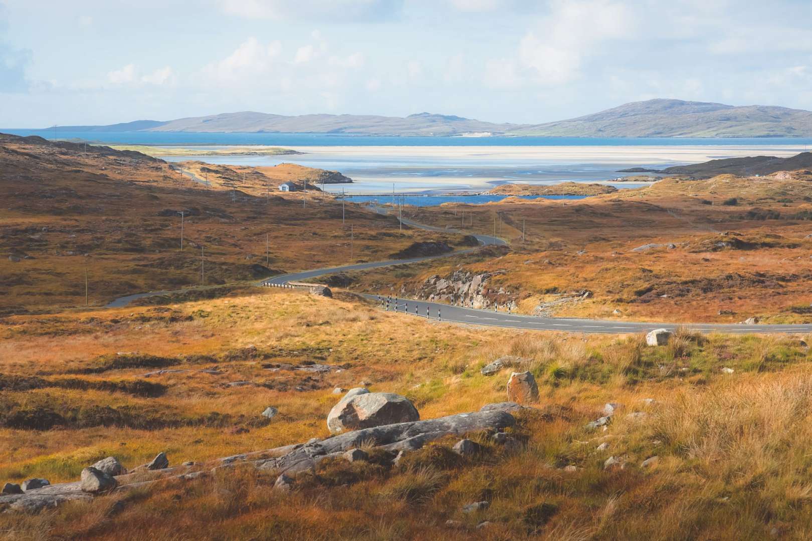 Eine Straße führt durch eine trockene Landschaft mit einem See im Hintergrund