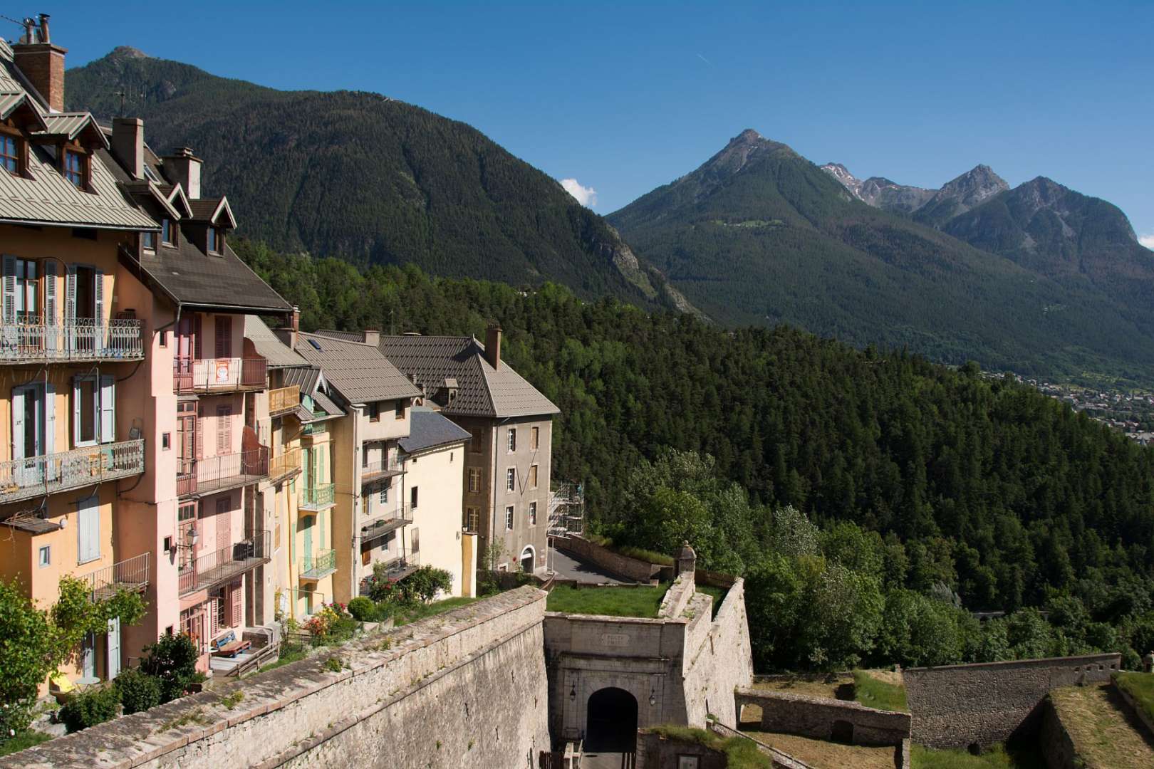 Eine Reihe von Häusern auf einem Hügel mit Bergen im Hintergrund