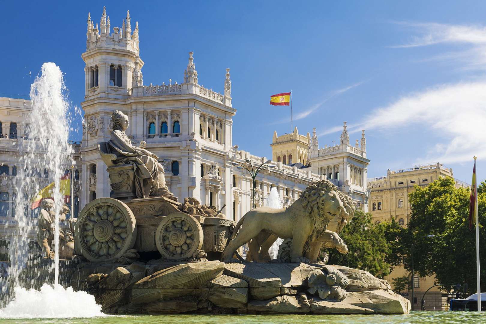 Ein Brunnen mit Löwen und einer spanischen Flagge im Hintergrund
