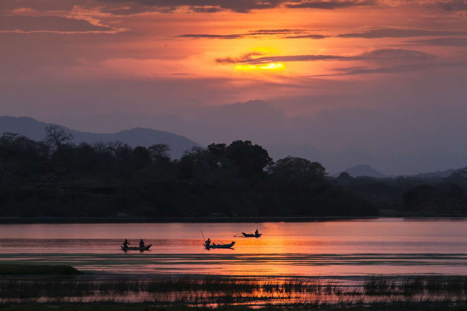 Eine Gruppe von Menschen in kleinen Booten auf einem See bei Sonnenuntergang