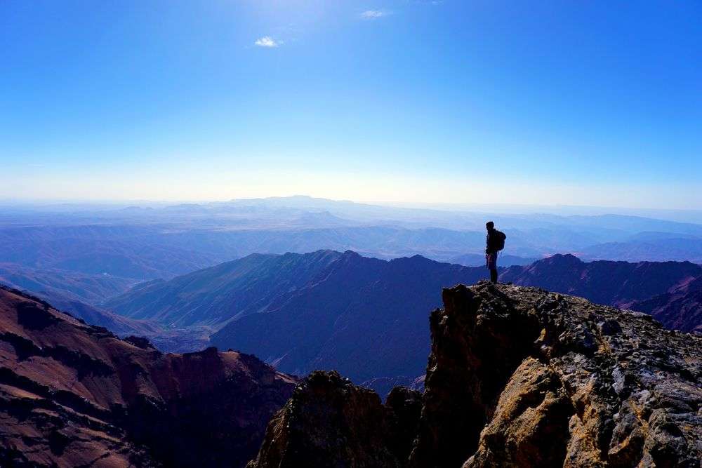 Ein Mann steht auf einer Klippe mit Blick auf eine Bergkette