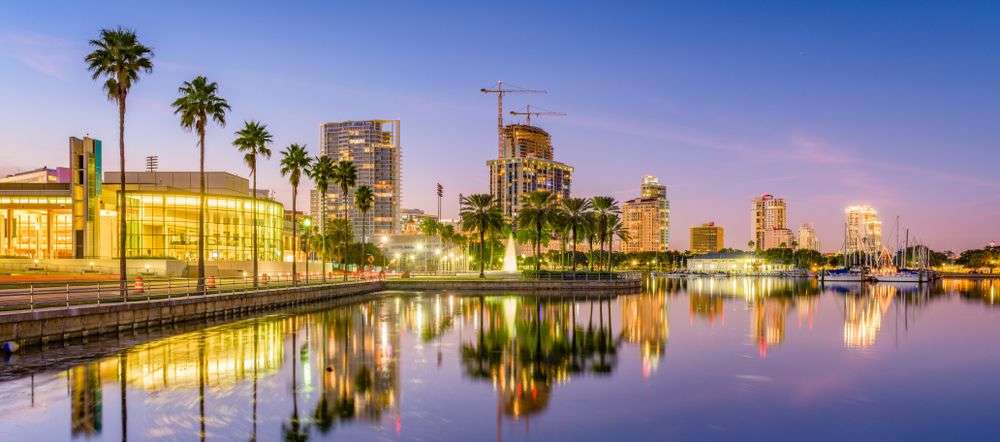 Eine Stadt mit vielen Gebäuden und Palmen spiegelt sich im Wasser