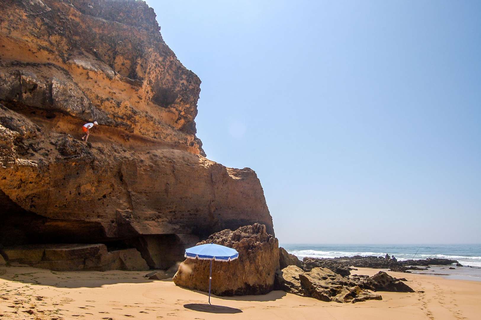 Ein Mann klettert auf einen Felsen an einem Strand