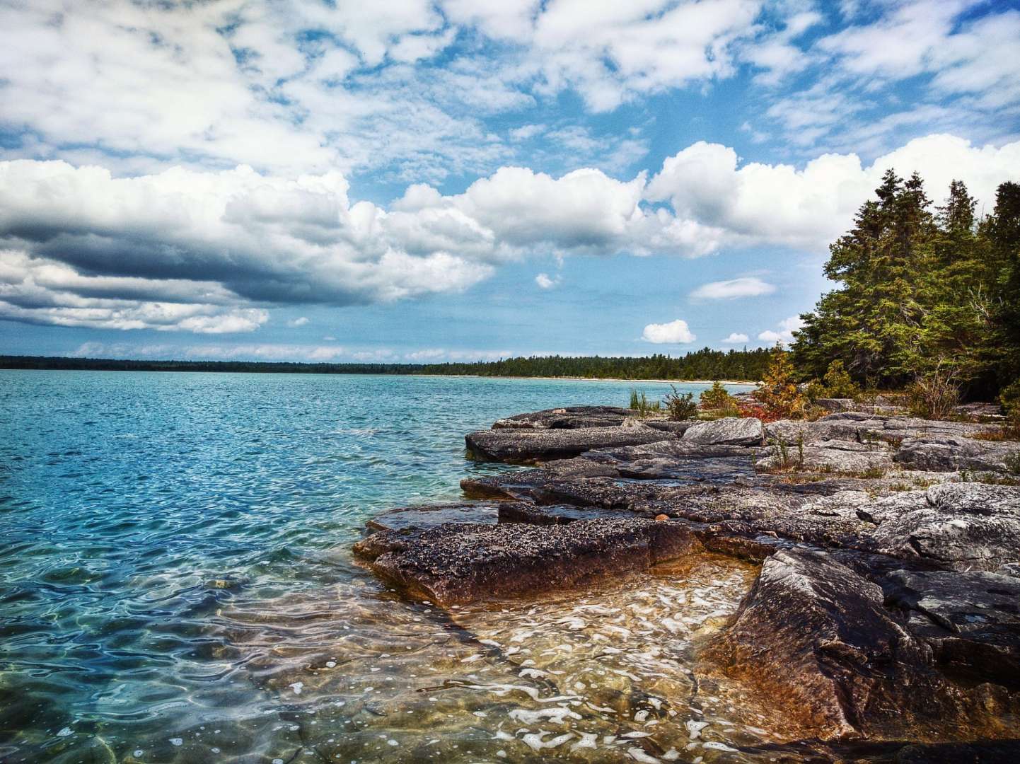 Ein See mit Felsen am Ufer und einem bewölkten Himmel