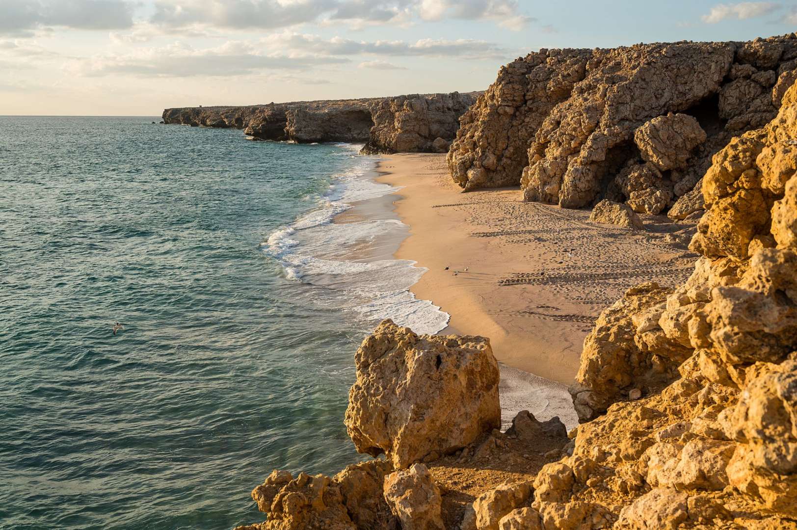 Ein Strand mit einem großen Felsen im Vordergrund