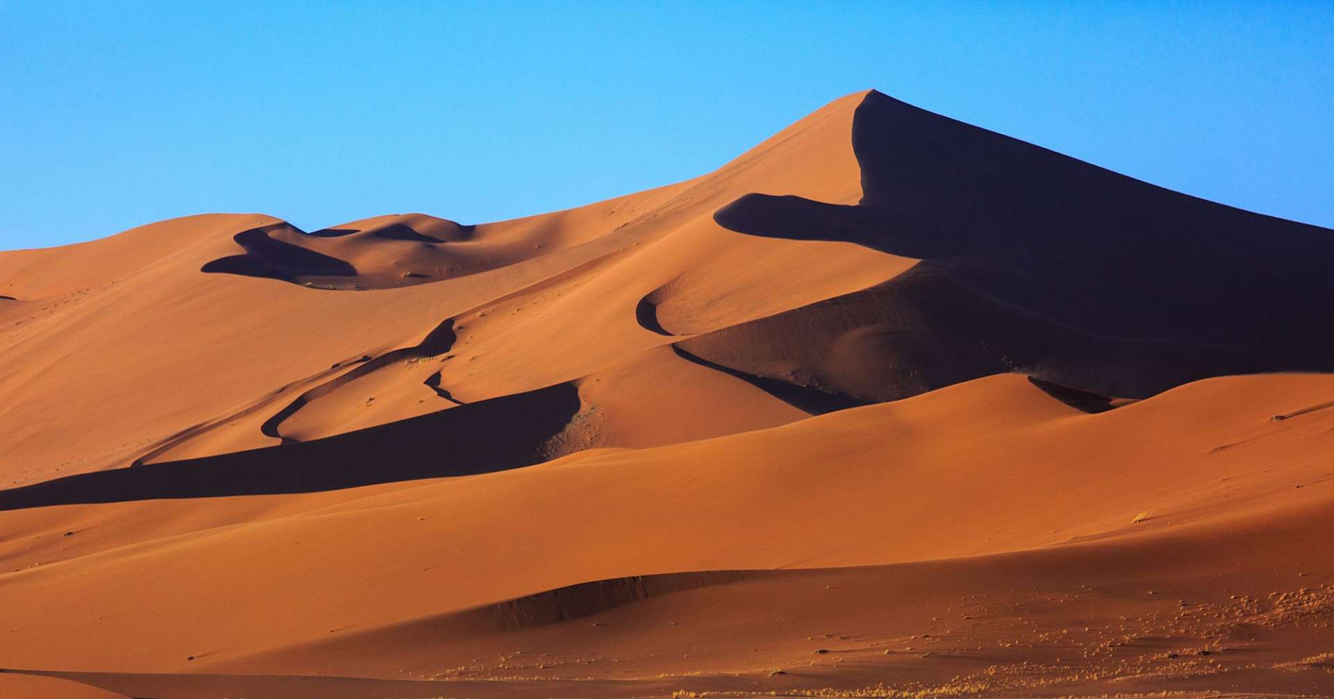 Eine große Sanddüne mit einem blauen Himmel dahinter