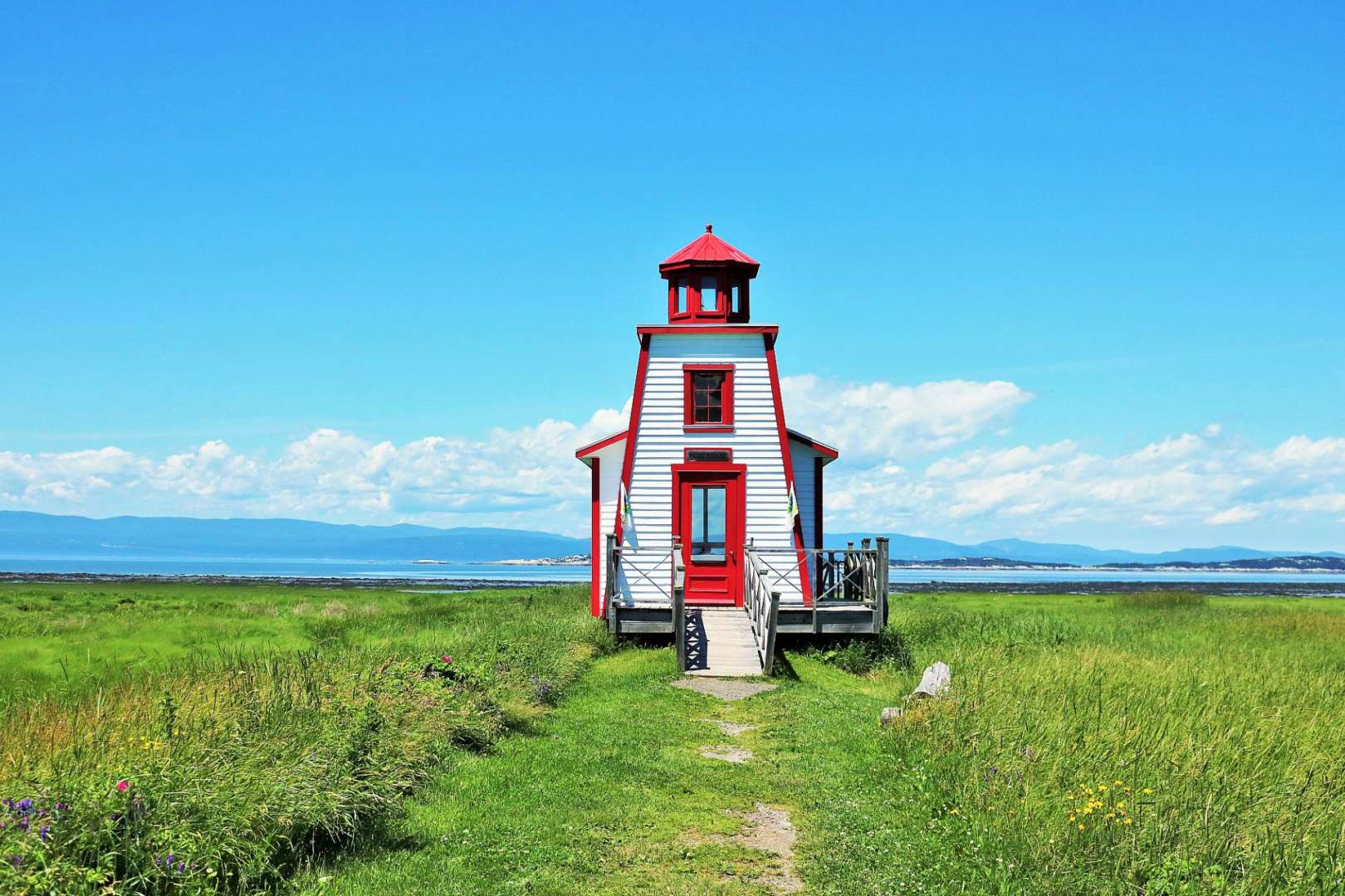 Ein rot-weißer Leuchtturm steht inmitten eines grünen Feldes