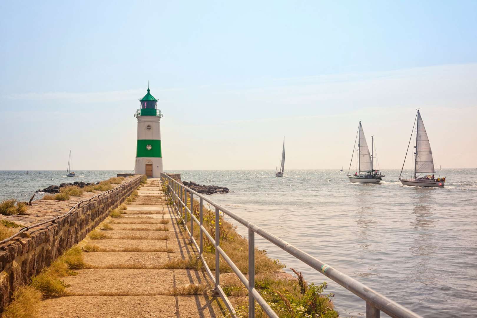 Ein Leuchtturm mit einem grünen Dach steht an einem Pier