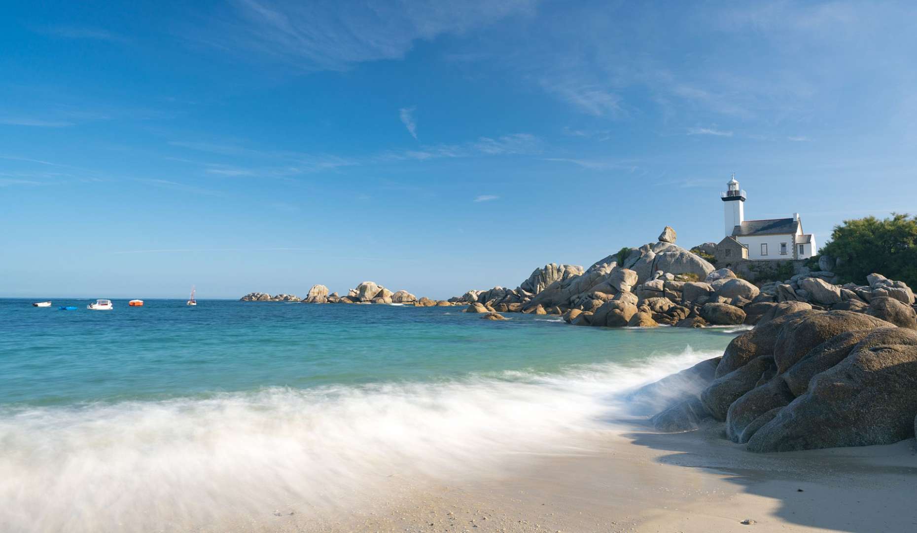Ein Leuchtturm sitzt auf einem Felsen über einem Strand