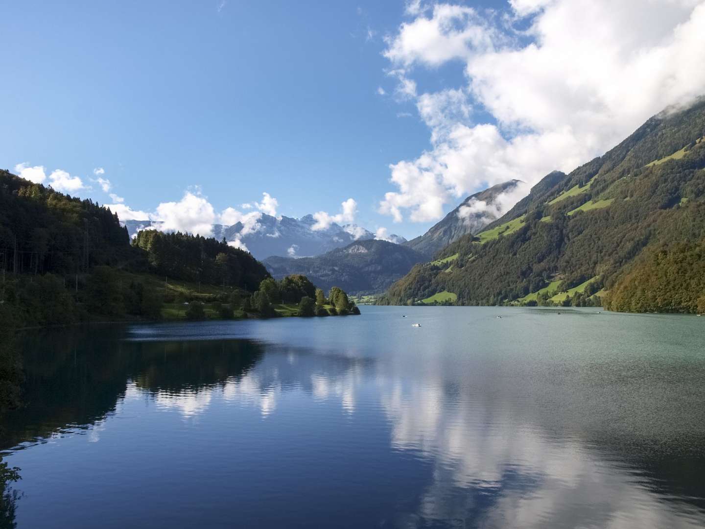 Ein See mit Bergen im Hintergrund und einem blauen Himmel mit Wolken