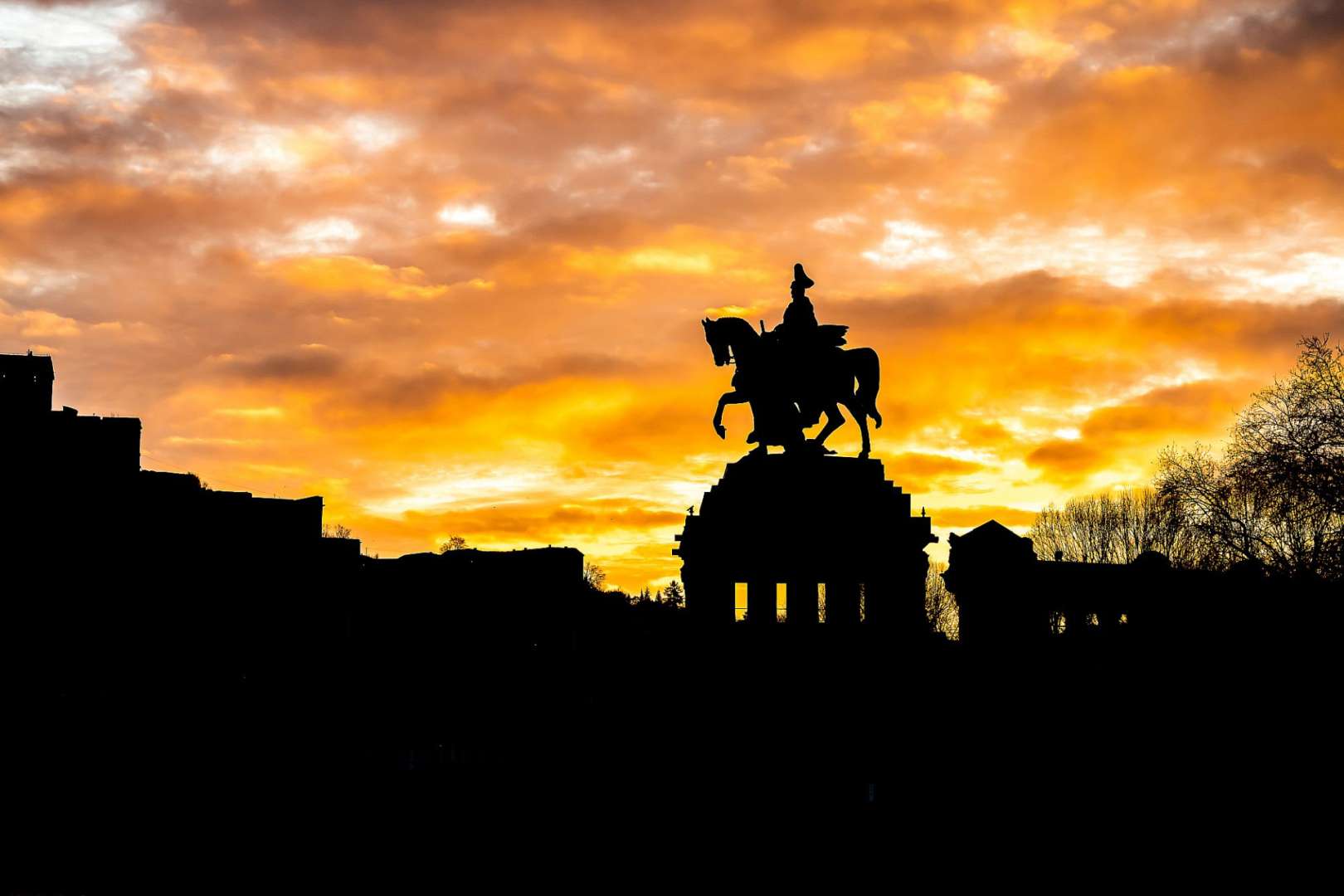 Eine Silhouette einer Statue eines Mannes auf einem Pferd bei Sonnenuntergang