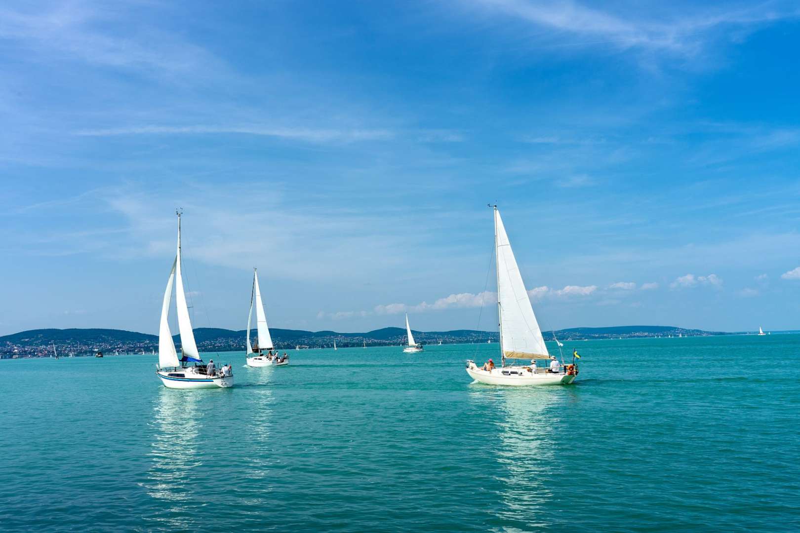 Drei weiße Boote mit weißen Segeln schwimmen im Ozean