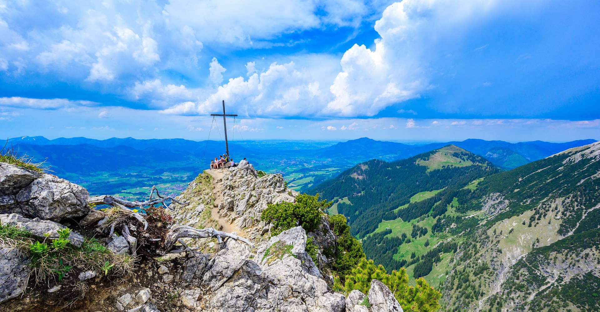 Menschen stehen auf einem Berg mit einem Kreuz darauf