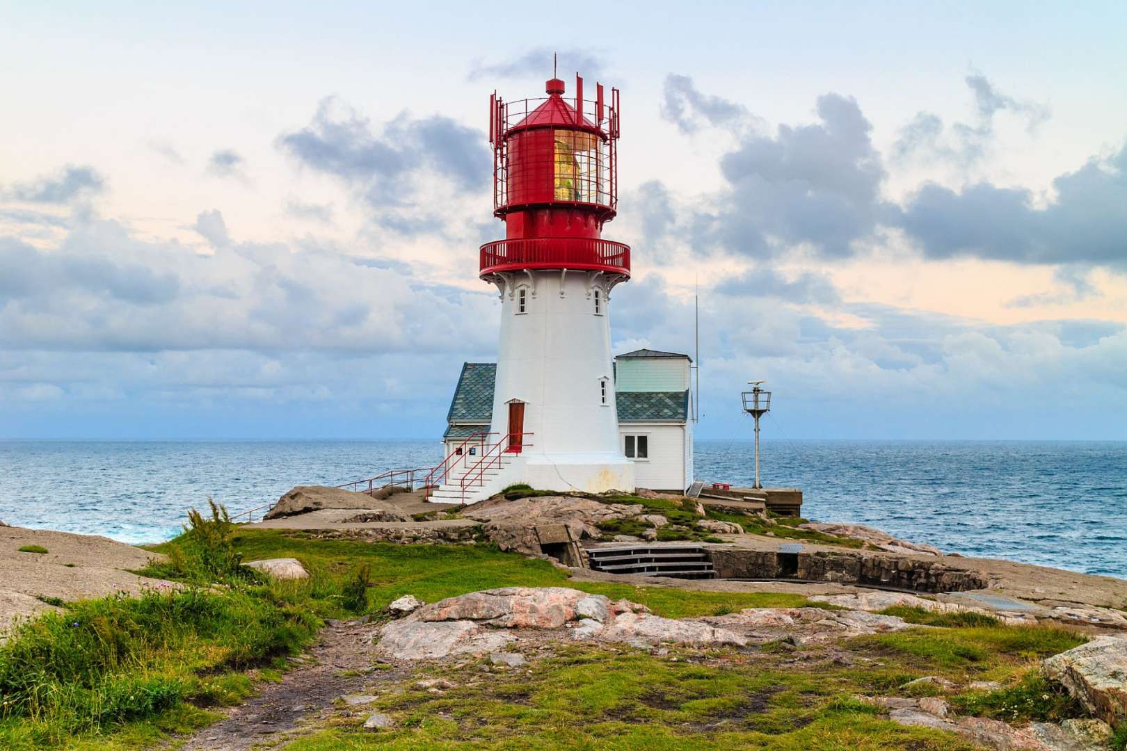 Ein rot-weißer Leuchtturm steht auf einem Felsen in der Nähe des Ozeans