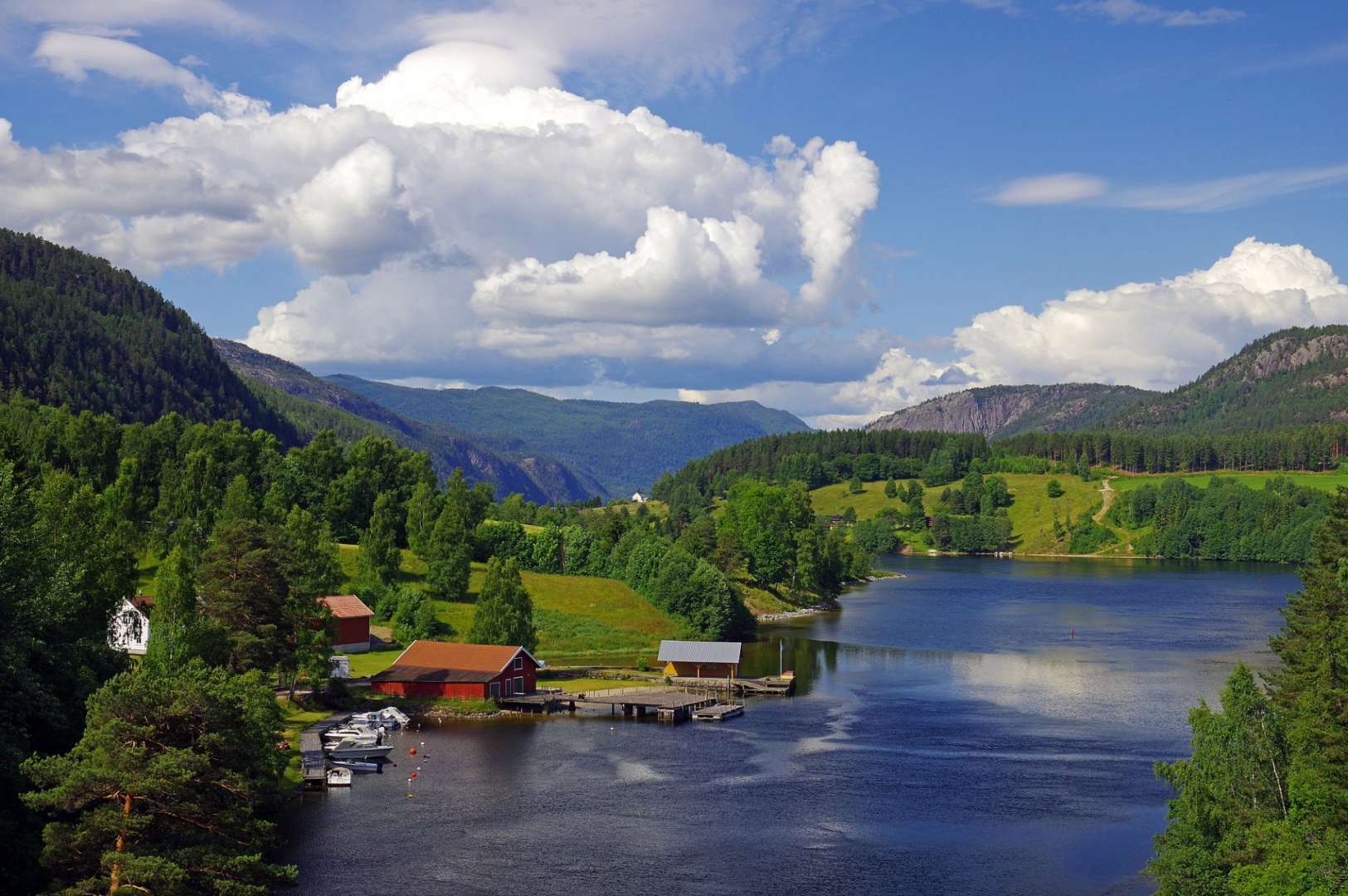 Ein See mit roten Häusern am Ufer und Bergen im Hintergrund