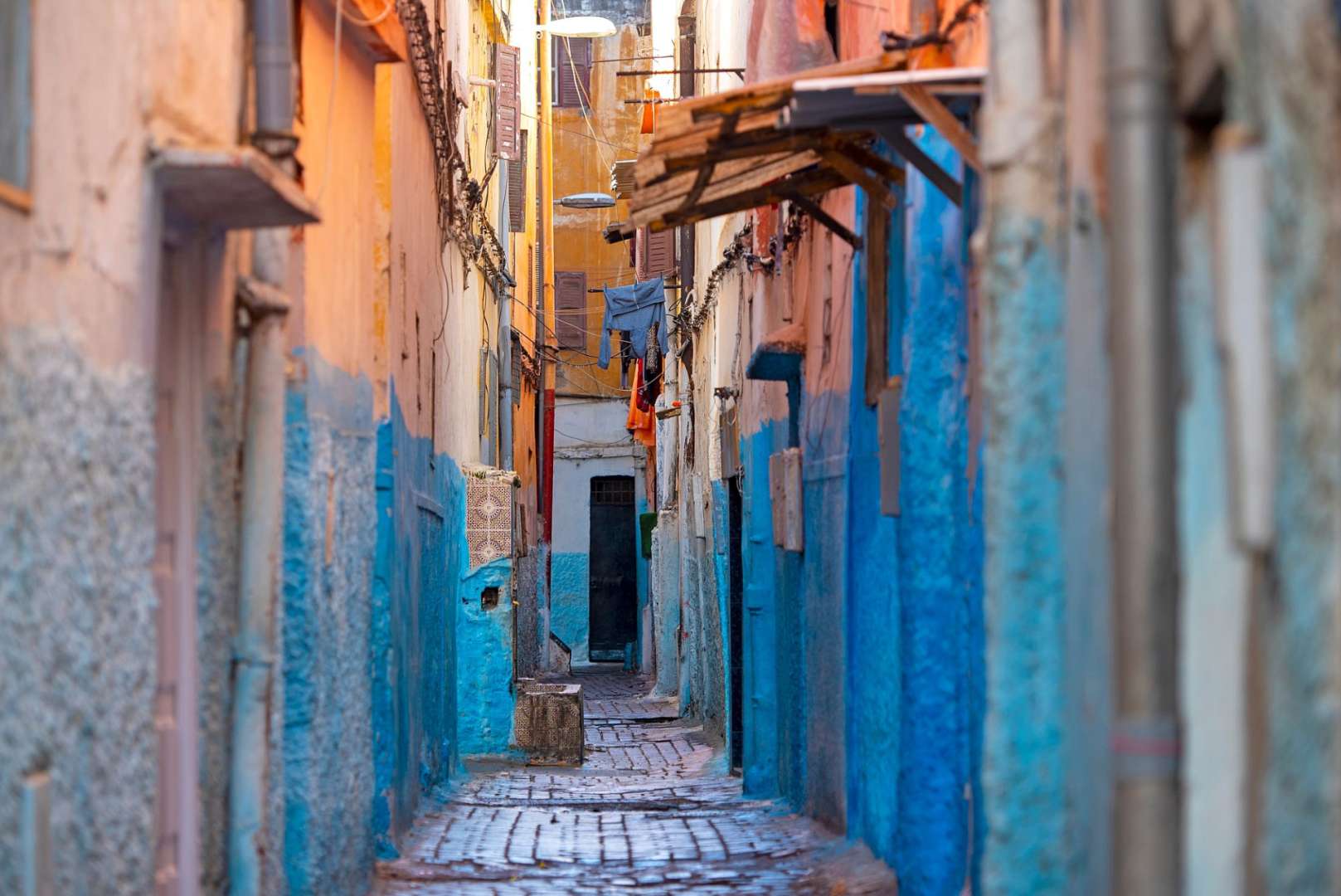 Eine schmale Straße mit blauen Wänden und orangefarbenen Gebäuden