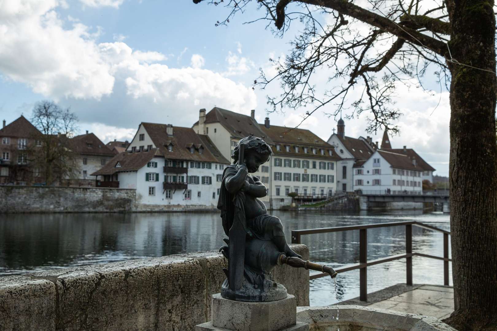 Eine Statue einer Frau sitzt neben einem Fluss