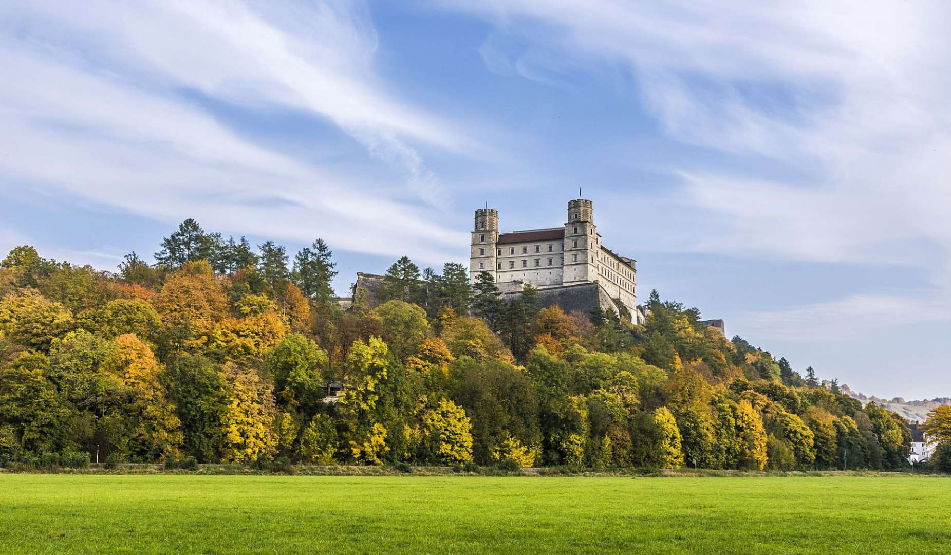 Ein großes Schloss sitzt auf einem Hügel über einem Feld