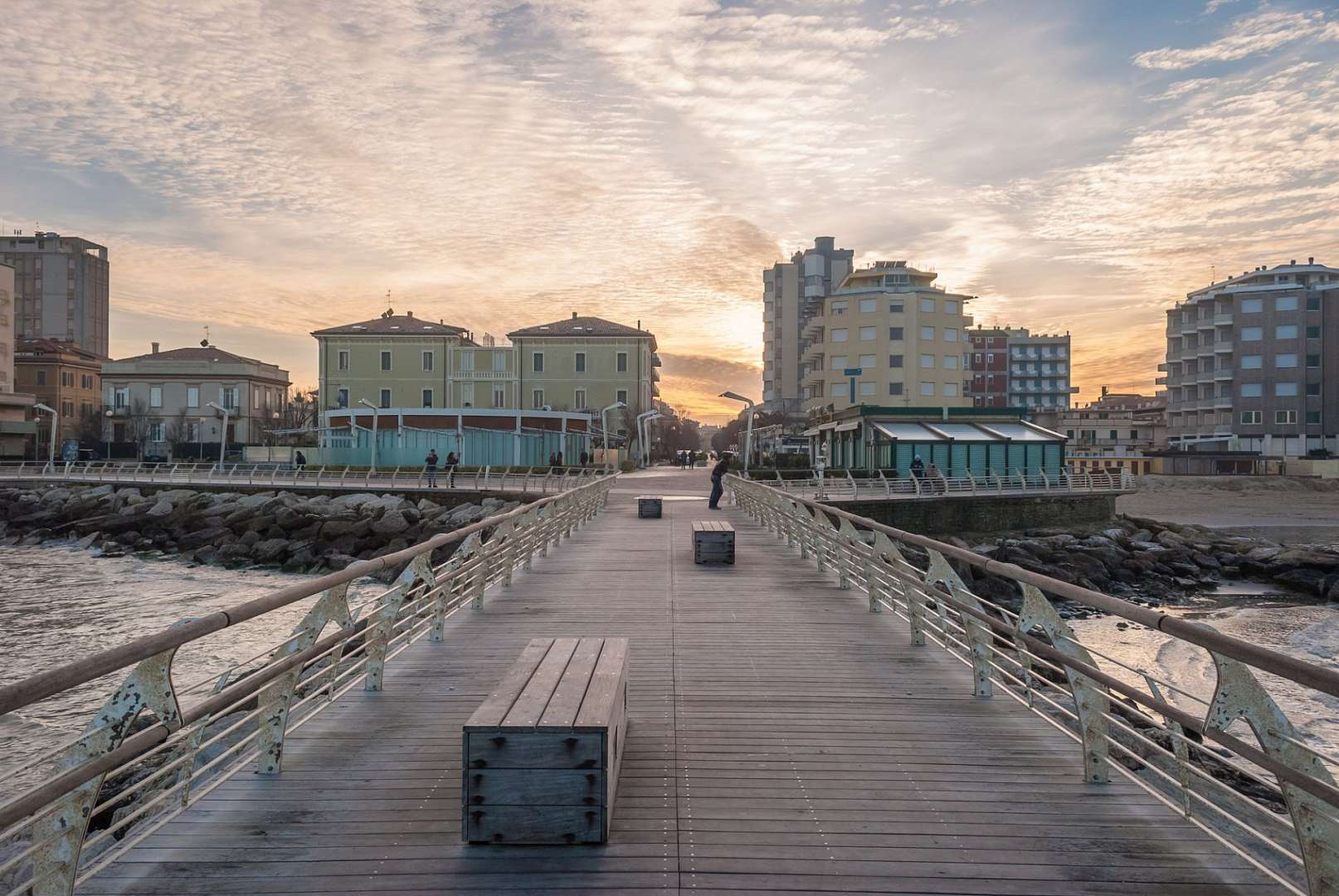 Ein Mann steht auf einem Pier mit Bänken und Gebäuden im Hintergrund