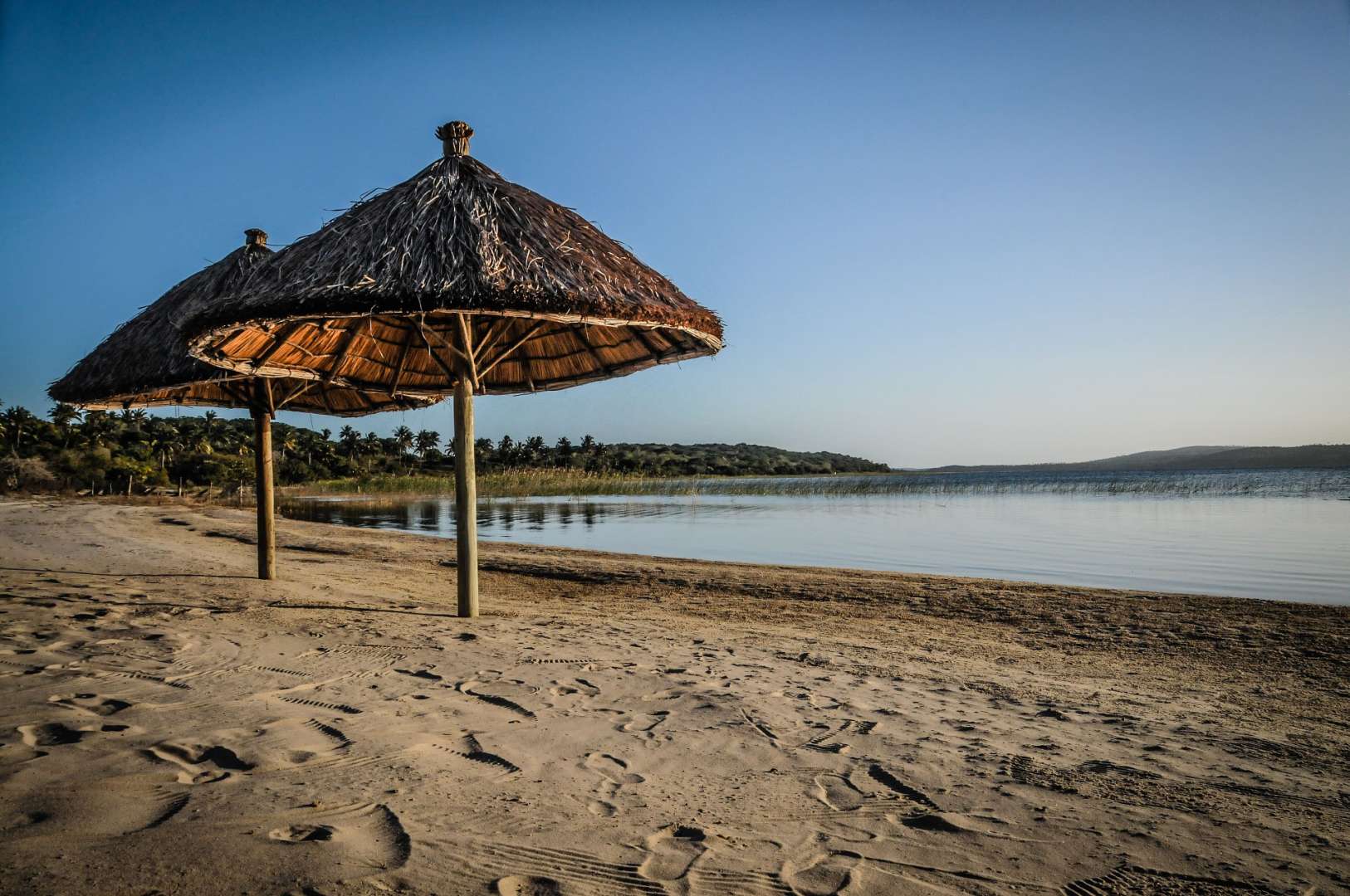 Ein Strand mit Strohschirmen und einem See im Hintergrund