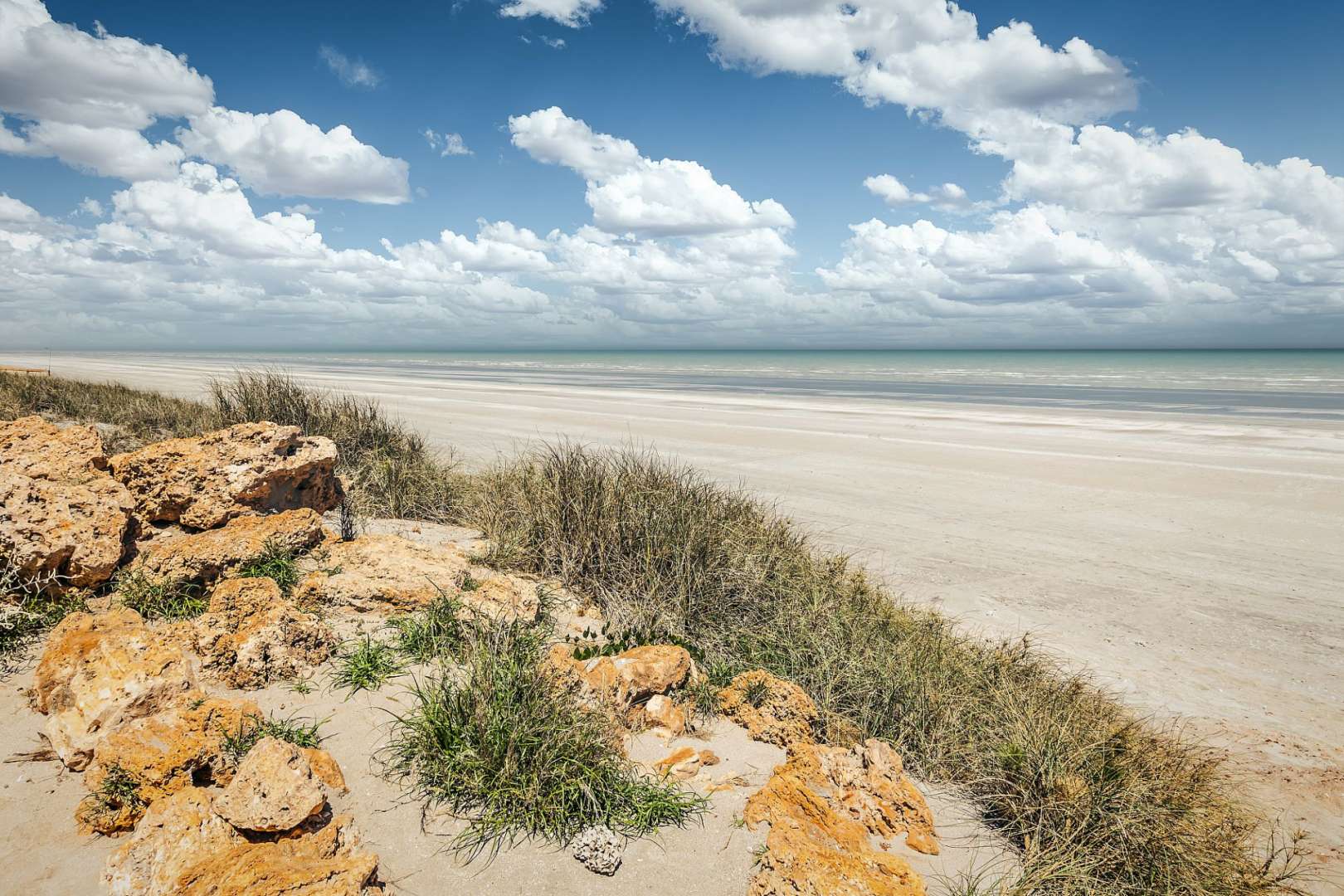 Ein Strand mit einem blauen Himmel und weißen Wolken
