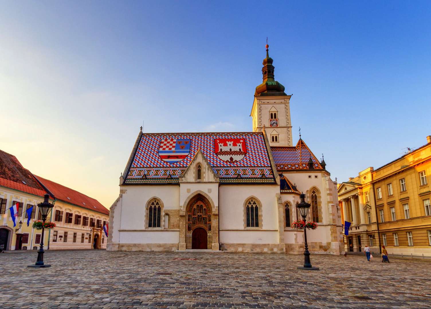 Eine Kirche mit einem bunten Dach und Wappen darauf