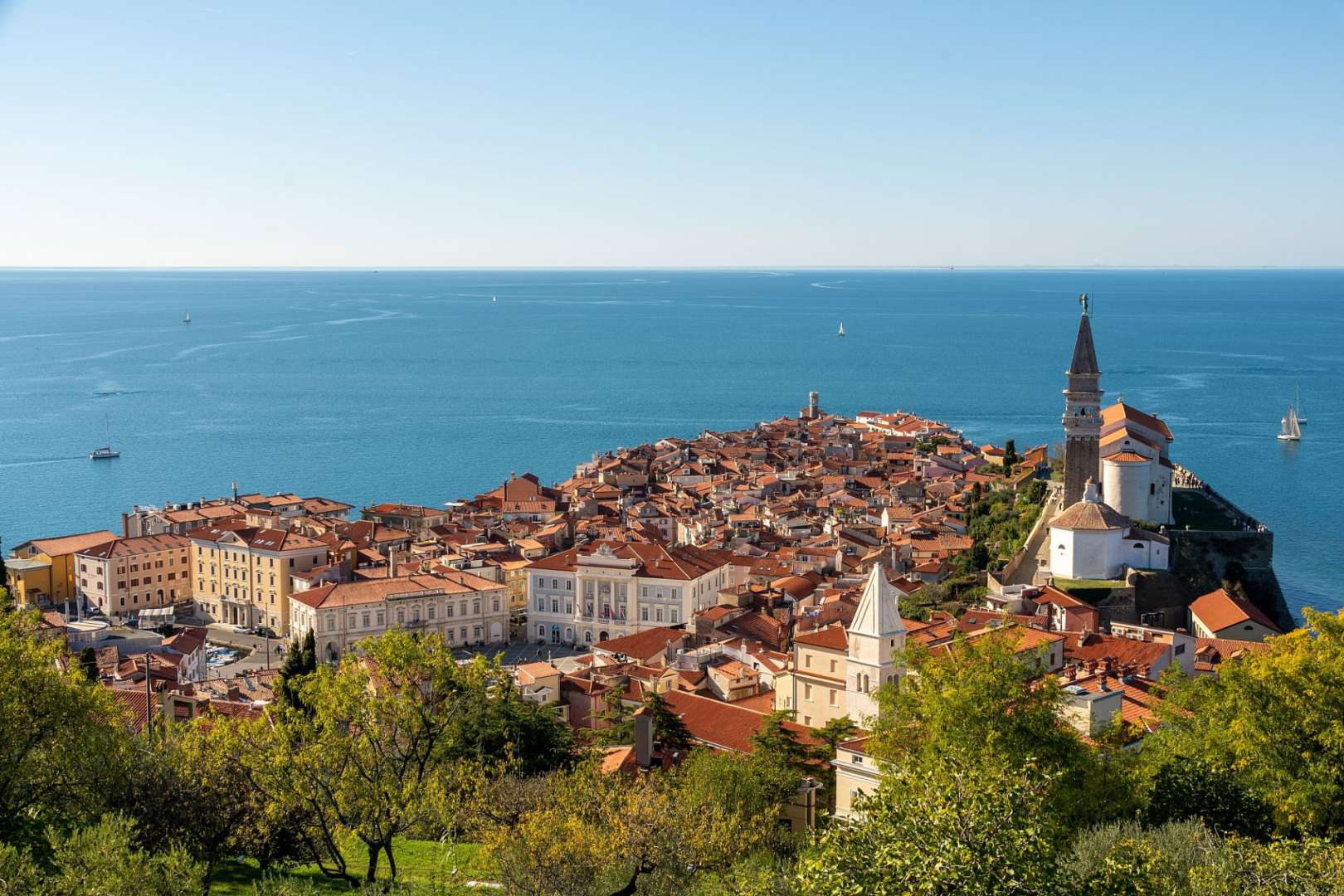 Eine Stadt mit roten Dächern und einem weißen Turm in der Nähe des Ozeans
