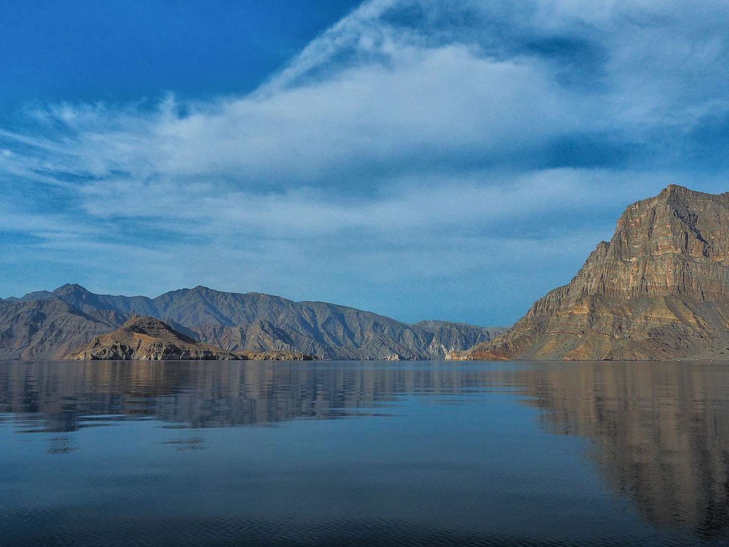 Ein See mit Bergen im Hintergrund und einem blauen Himmel mit Wolken
