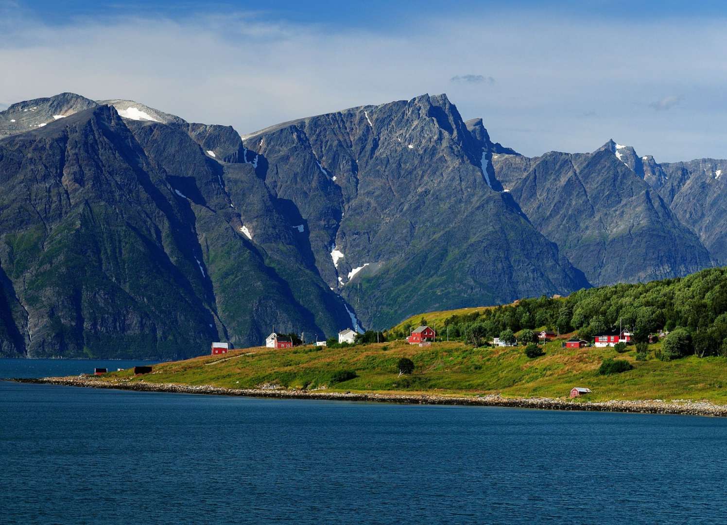 Ein kleines Dorf an der Küste mit Bergen im Hintergrund