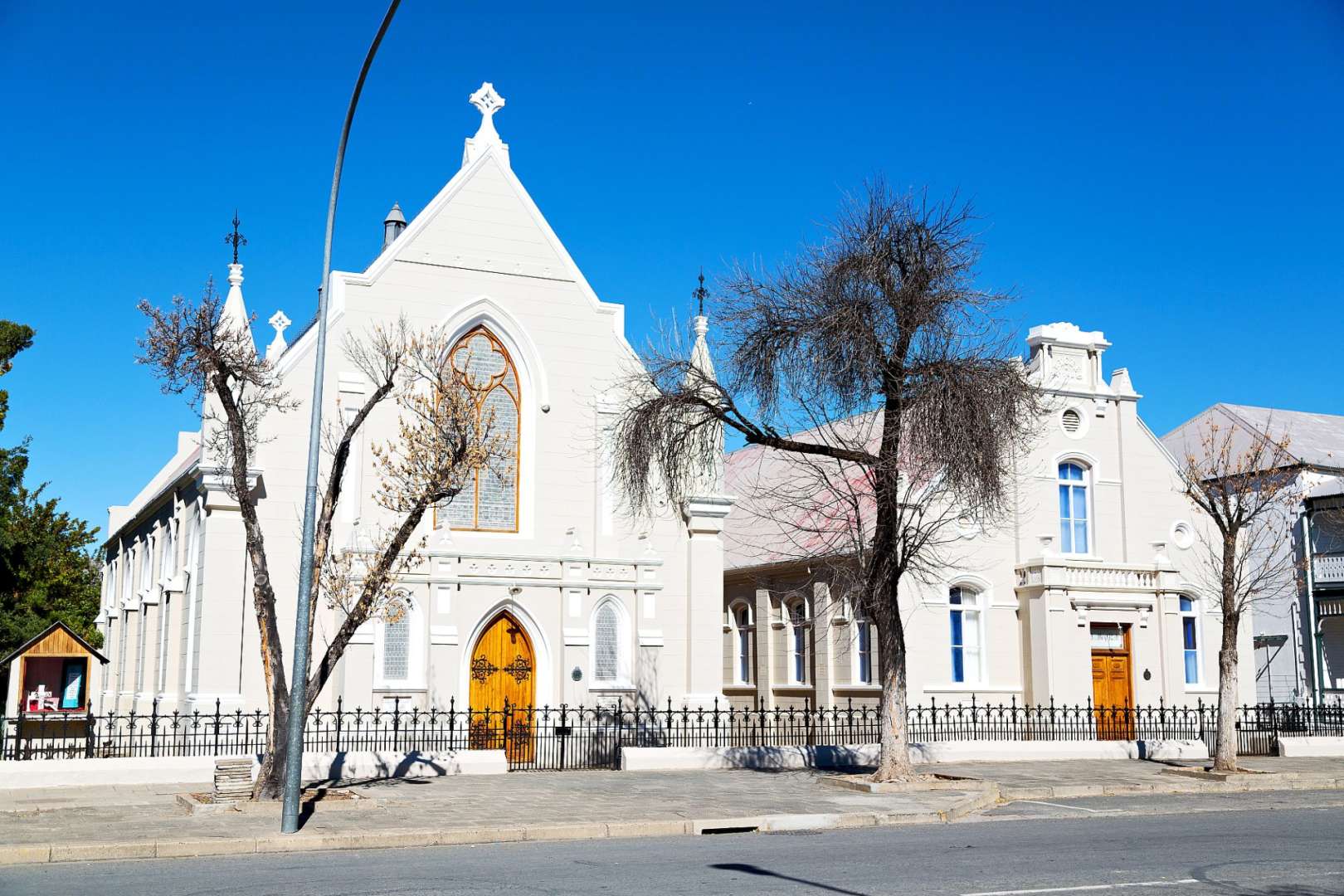 Eine weiße Kirche mit einem eisernen Zaun umgeben von Bäumen